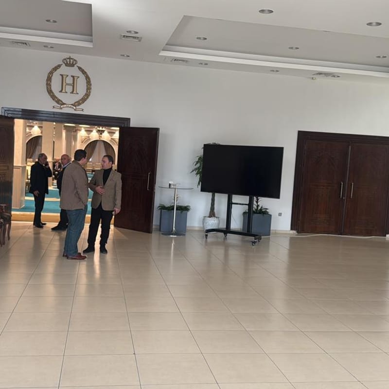 Grand lobby interior with H Venue gold crown logo, dark wood doors opening to event hall
