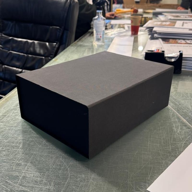 Premium matte black custom gift box with textured finish on desk in print shop