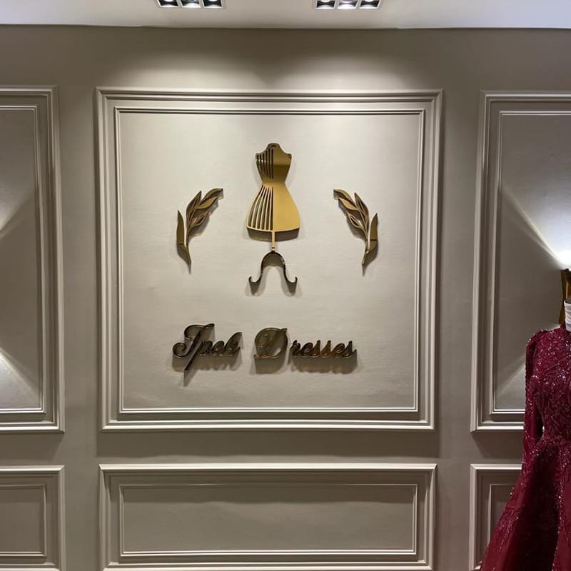 Gold dimensional dress-form logo and lettering mounted on a white panelled boutique wall