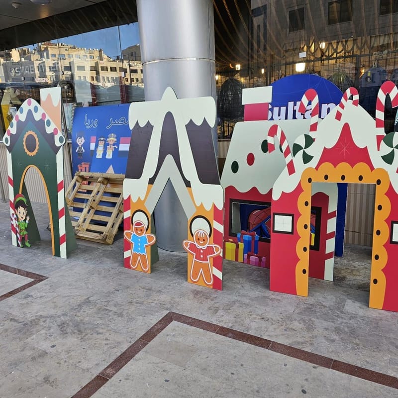 Life-size gingerbread house cutouts with candy cane trims and gingerbread figures outside a glass shopfront