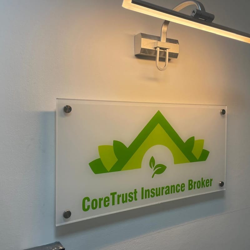 Frosted acrylic CoreTrust Insurance Broker wall plaque with green logo, mounted on stand-off bolts