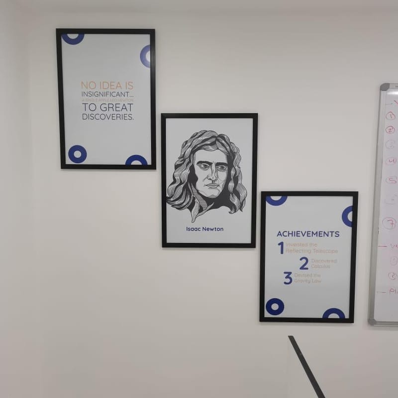 Set of framed educational prints featuring Isaac Newton portrait, quote, and achievements for school display
